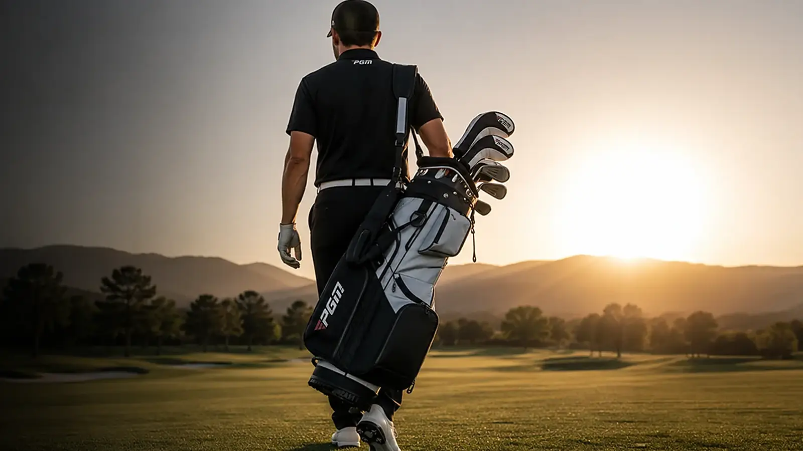 Golfista con bolsa PGM caminando la cancha al atardecer.